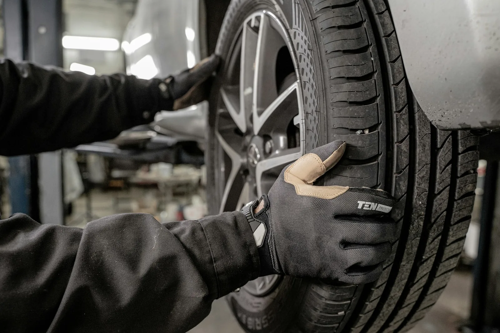 A technician in gloves handling a wheel in the workshop
